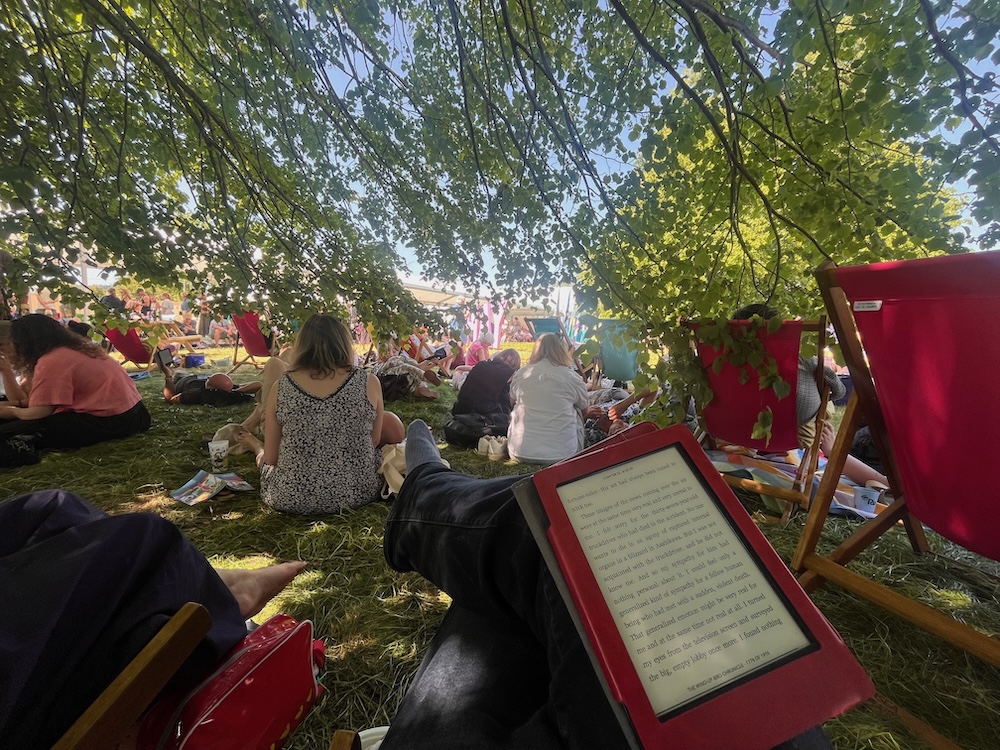Reading an ebook in the dappled shade along with many of festival goes, some in deckchairs